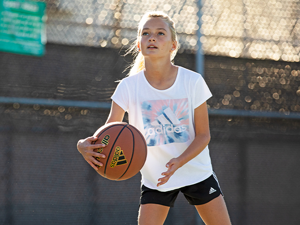 Young girl playing basketball in adidas Youth Apparel